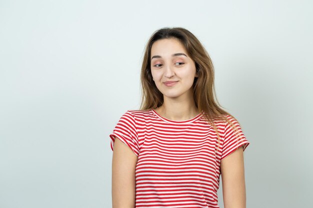 Das Porträt eines schönen Mädchens in einem gestreiften T-Shirt sieht mit nachdenklicher Miene beiseite und erwägt einen Plan für weitere Maßnahmen