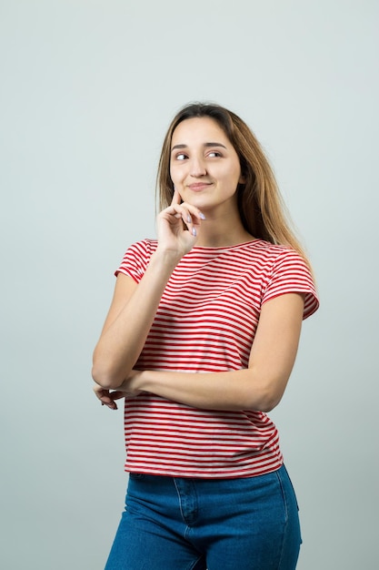 Das Porträt eines schönen Mädchens in einem gestreiften T-Shirt sieht mit nachdenklicher Miene beiseite und erwägt einen Plan für weitere Maßnahmen