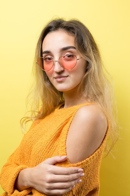 Das porträt eines schönen mädchens in einem orangefarbenen pullover sieht mit nachdenklicher miene beiseite und erwägt einen plan für weitere maßnahmen