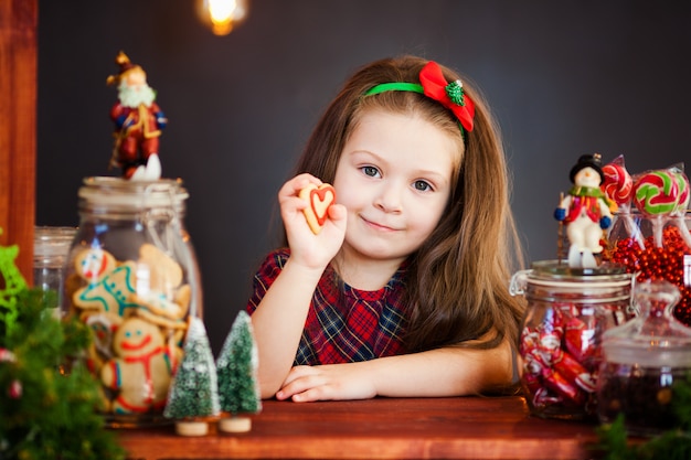 Das portrai des netten kleinen Mädchens nahe Weihnachten decoratoins mit Lebkuchen