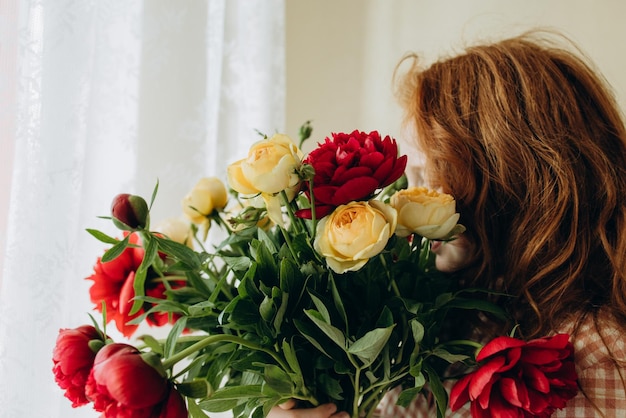 Das rothaarige Mädchen versteckte ihr Gesicht in einem rotgelben Blumenstrauß