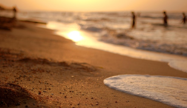 Das sandige Ufer des Asowschen Meeres bei Sonnenuntergang ein warmer Sommerabend die Wellen schlagen gegen das Ufer und streicheln den Sand mit Meerschaum-Defokussierung selektiver Fokus