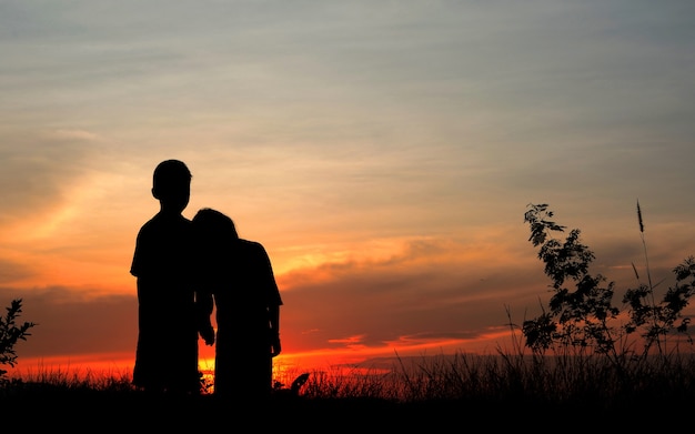 Das Schattenbild der Jungen und der Mädchen, die den Sonnenuntergang überwachen.