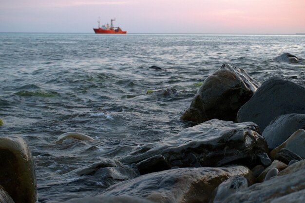 Das Schiff vor dem Hintergrund der rosa Wolken bei Sonnenuntergang segelt auf den Wellen Sommerabend Wunderschöne Märchenlandschaft Schwarzes Meer Russland