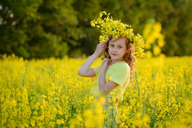 Das schöne Mädchen in einem gelben Kleid auf dem blühenden Feld