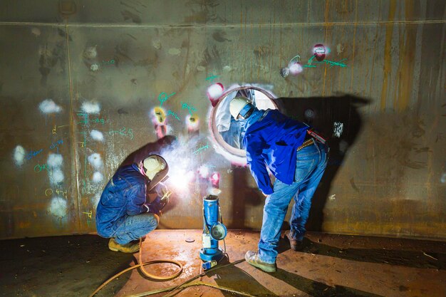 Das Schweißen des Metalllichtbogens eines männlichen Arbeiters ist Teil des Baus von Erdöl- und Gaslagertanks für Maschinentankschächte im Inneren des geschlossenen Behälters