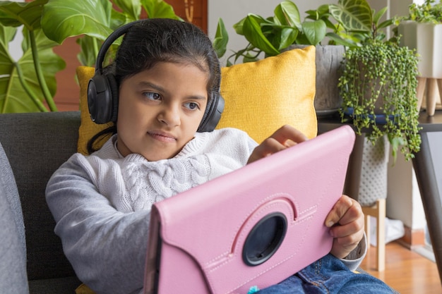 Das sitzende kleine Mädchen spielt mit ihrem Tablet