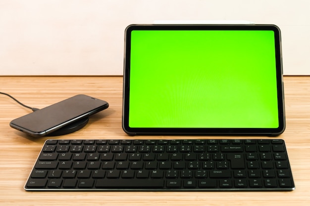 Das Smartphone wird beim kabellosen Laden neben dem Tablet und der Tastatur aufgeladen