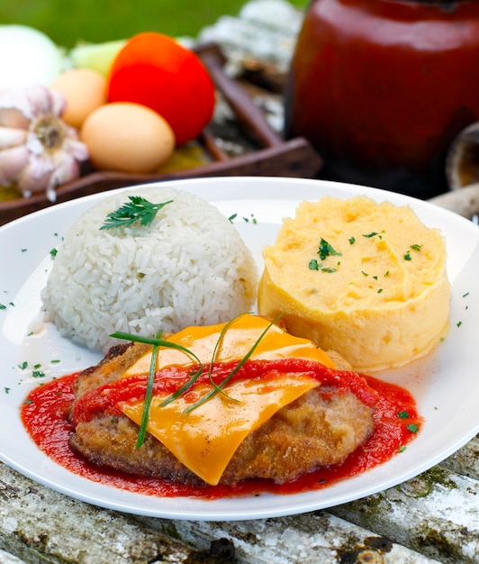 Das Steak Parmigiana mit Kartoffel und Reis