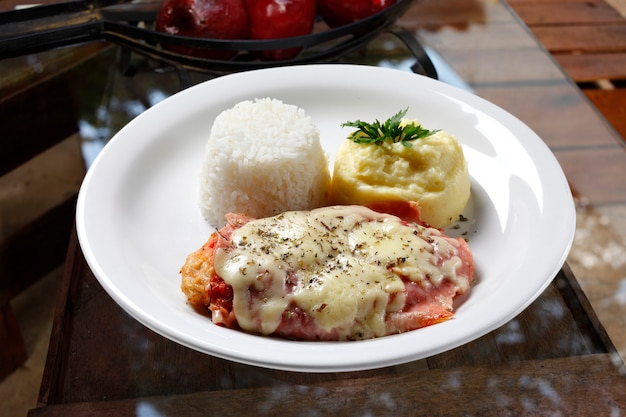 Das Steak Parmigiana mit Kartoffel und Reis