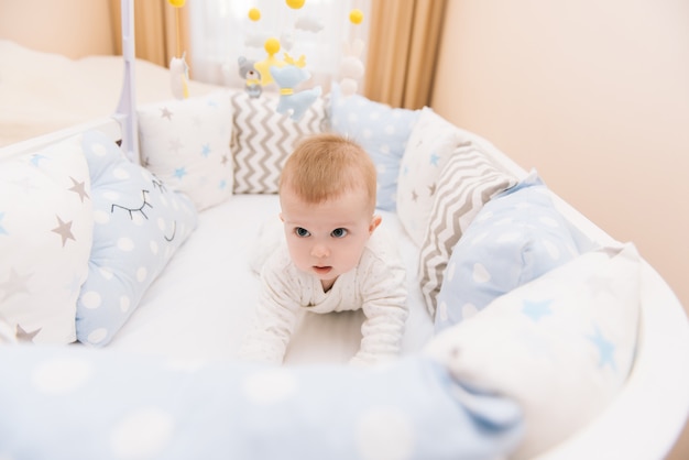 Das süße Baby liegt in einem weißen runden Bett. Leichter Kindergarten für kleine Kinder.