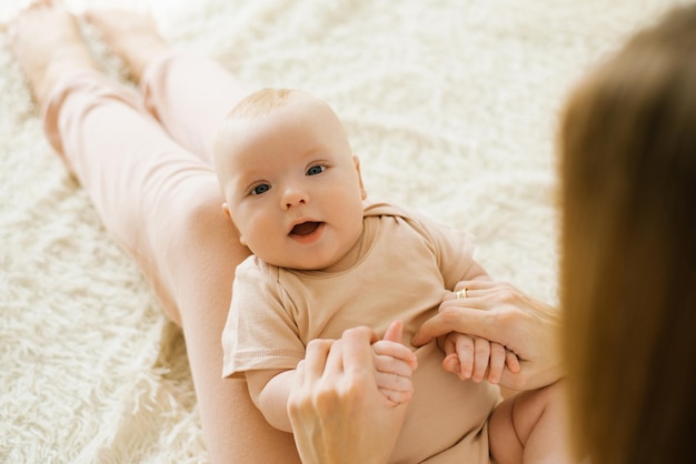 Das süße kaukasische Neugeborene liegt auf dem Schoß seiner Mutter und schaut mit einem Lächeln auf die Kamera Muttertagskonzept