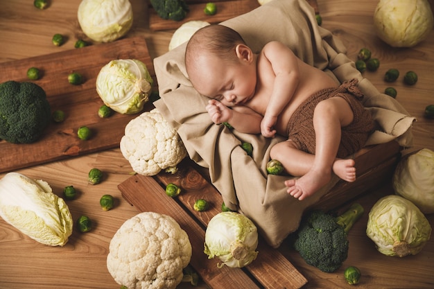 Das süße kleine Baby liegt in der Schachtel mit vielen verschiedenen Kohlköpfen