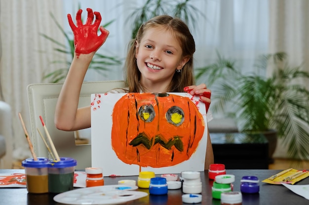 Das süße kleine Mädchen hält ein Poster mit bemaltem Halloween-Kürbis.