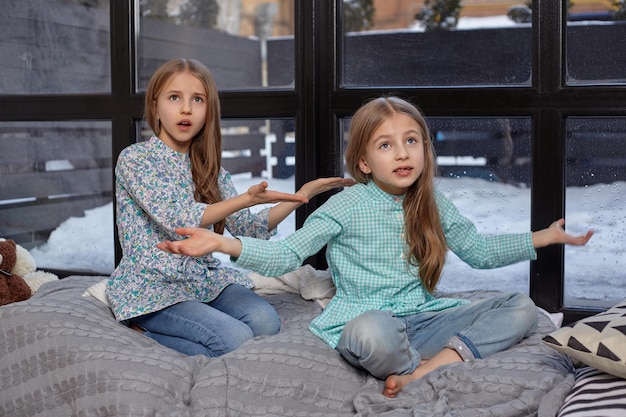 Das süße kleine Mädchen schnüffelt auf ihre Schwester und zeigt mit dem Finger auf sie