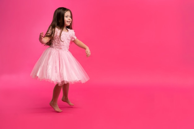 Das süße kleine Mädchen träumt davon, eine Ballerina zu werden. Kleines tanzendes Mädchen. Studio-Shooting über rosa Hintergrund.