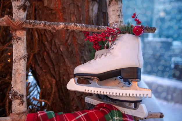Das Symbol der weihnachtlichen Winterferien sind Eiskunstlaufschuhe. Weiße Damen-Eiskunstlaufschuhe als Dekoration für das neue Jahr auf der Straße