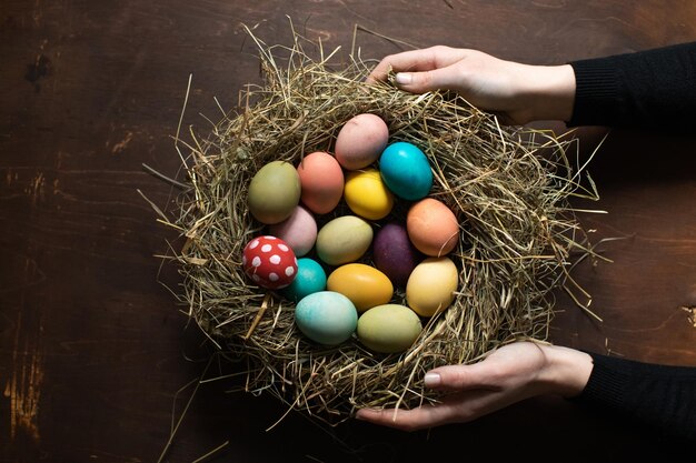 Das Symbol von Ostern Eine Frau hält ein Nest mit farbigen Ostereiern