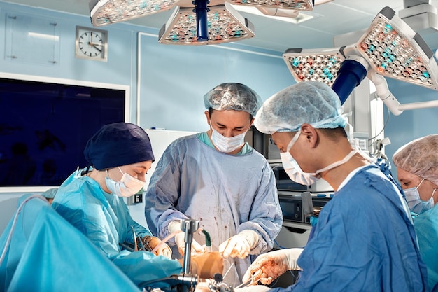 Das Team der Chirurgen beugte sich während eines komplexen chirurgischen Eingriffs in einem sterilen Operationssaal über Pati