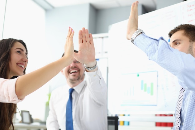 Das Team klatscht in die Hände und gibt High Five, um das abgeschlossene Geschäftsprojekt zu feiern