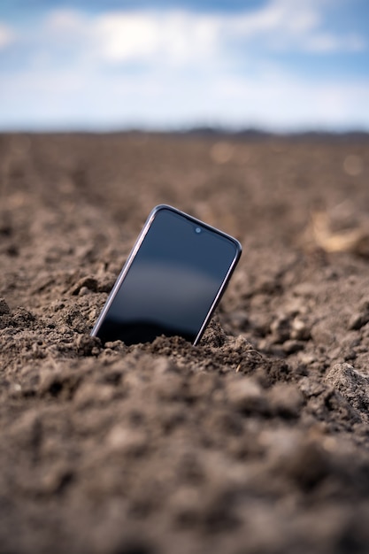 Das Telefon ragt auf dem Feld aus dem Boden.