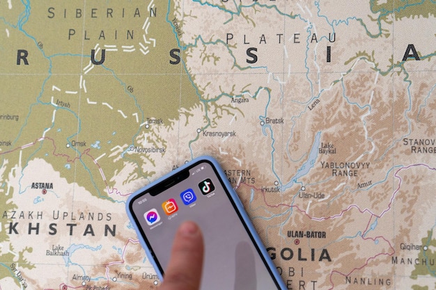 Das Tik Tok-Logo auf dem Smartphone-Bildschirm vor dem Hintergrund der Karte von Russland