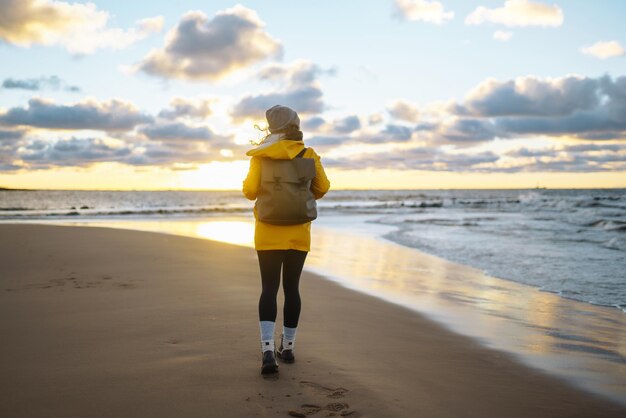 Das Touristenmädchen in einer gelben Jacke posiert am Meer auf einem Abenteuer.