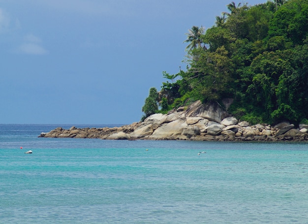 Das türkisfarbene Meer wäscht den Felsen mit großen Steinen und bedeckt mit Grün. Landschaft der Andamanensee Thailand. Platz zum Kopieren von Text.