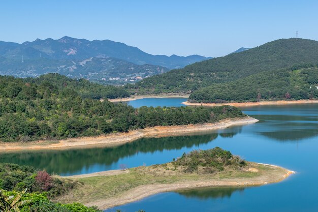 Das Ufer des Sees ist grün, in der Mitte gibt es einige kleine Inseln und der Himmel und das Wasser sind blau