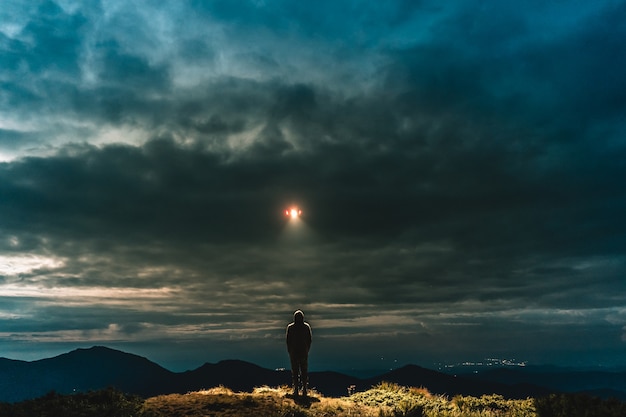 Das UFO glänzt auf einem auf dem Berg stehenden Männchen