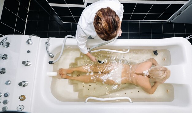 Das Verfahren der Unterwasser-Duschmassage im Badezimmer. Mädchen über das Verfahren der Unterwassermassage.