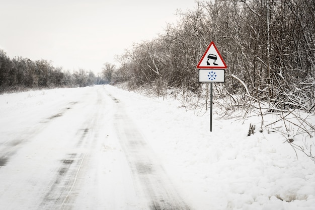 Das Verkehrsschild warnt vor einer rutschigen Straße aufgrund von Schneeeis.