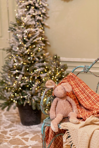 Das verschneite Haus wird für das neue Jahr geschmückt. Vintage Winterhof, geschmückt mit Weihnachtsbäumen, Laternen und einer gemütlichen Bank mit Decken und einem Plüschhasen. Weicher selektiver Fokus.