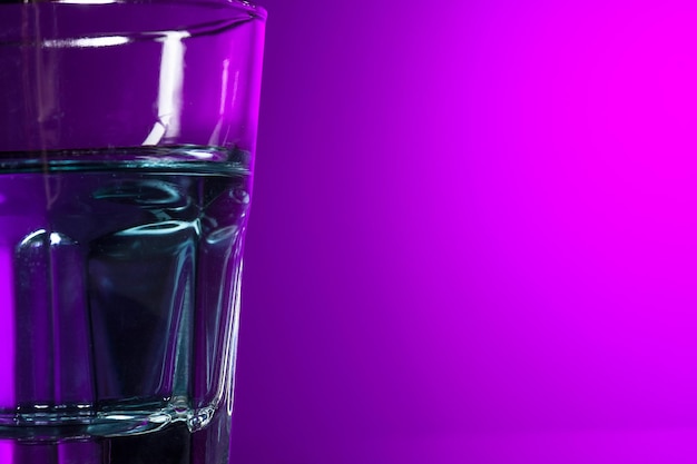 Das Wasser im Glas auf lila Hintergrund