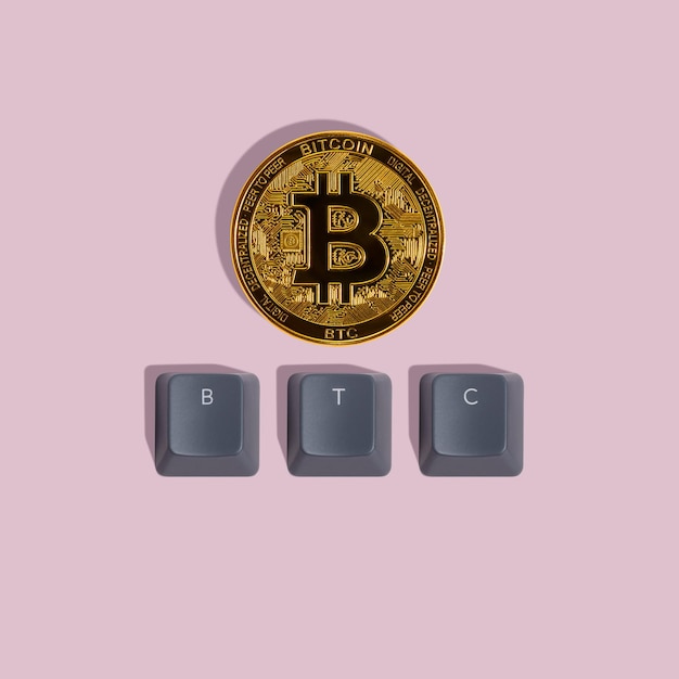 Das Wort BTC besteht aus grauen Tastaturkappen und Bitcoin-Münzen auf rosa Hintergrund