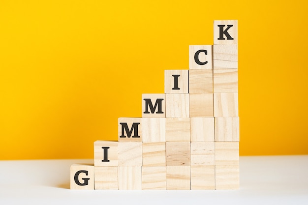 Das Wort-Gimmick ist auf einem Holzwürfel geschrieben. Blöcke auf einem leuchtend gelben Hintergrund. Unternehmenshierarchiekonzept und mehrstufiges Marketing. selektiver Fokus.