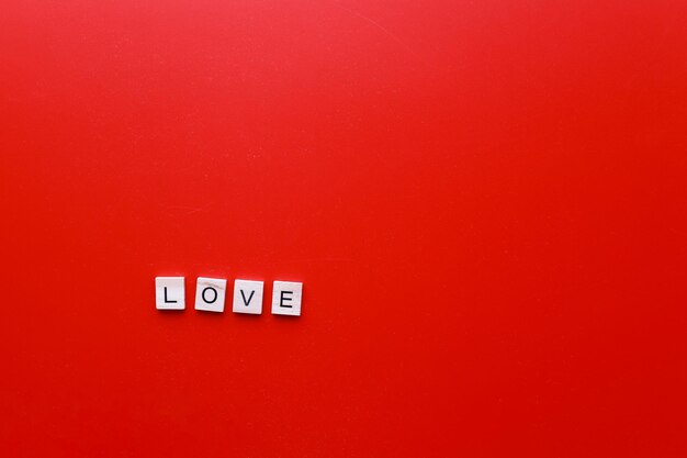 Das Wort Liebe aus hölzernen Buchstaben auf rotem Hintergrund ist Valentinstag
