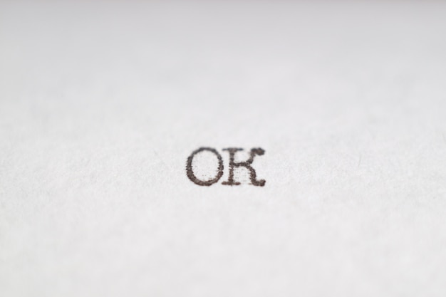 Das Wort "ok" wurde mit einer Retro-Schreibmaschine auf ein weißes Blatt Papier geschrieben