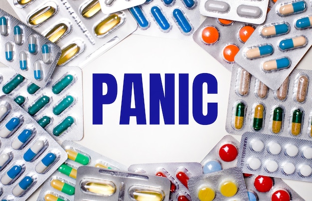Das Wort PANIC steht auf hellem Hintergrund, umgeben von mehrfarbigen Paketen mit Pillen. Medizinisches Konzept