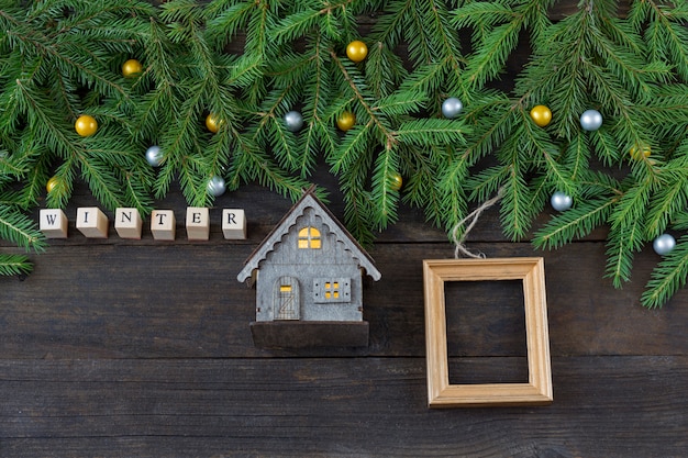 das wort winter aus holzbuchstaben, einem kleinen holzhaus und einem holzrahmen für ein foto