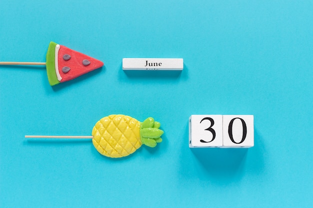 Data do calendário 30 de junho e frutas de verão abacaxi doce, pirulitos de melancia.