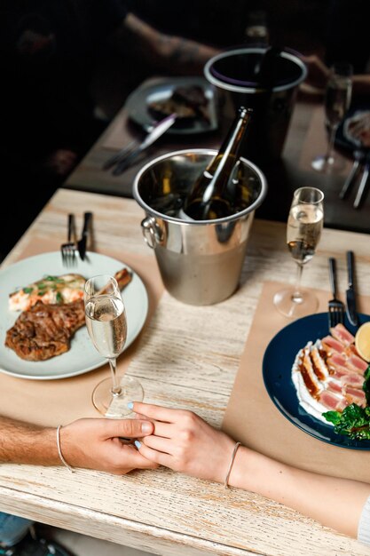 Foto data em um restaurante mãos de um homem e uma mulher em um jantar romântico à luz de velas