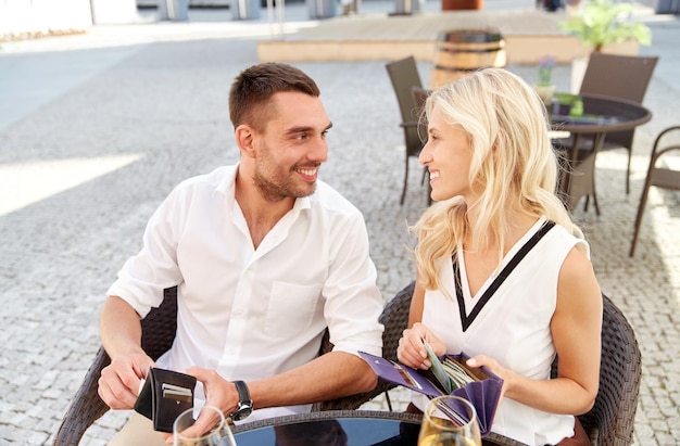 data, pessoas, conceito de pagamento e finanças - casal feliz com carteira e taças de vinho pagando conta no restaurante