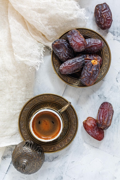 Dátiles secos en un plato de bronce y café negro