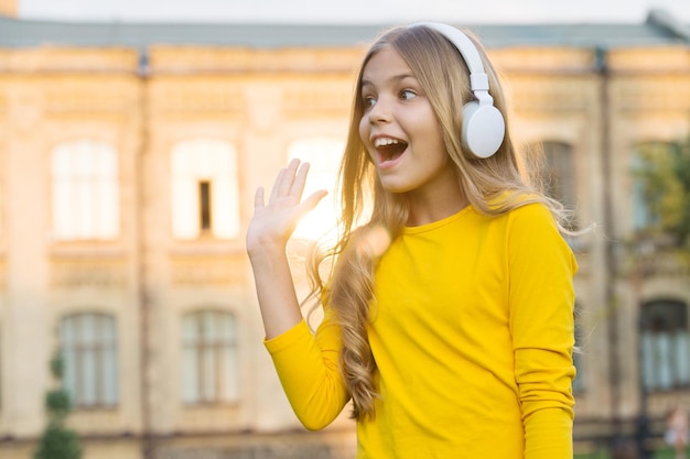 Dê a cinco Criança feliz a mão aberta cumprimentando ao ar livre Criança ouvindo música Tecnologia de som estéreo Nova tecnologia Vida moderna Tecnologia para se divertir Fique atento à tecnologia