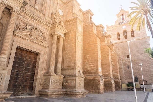 De baixo da antiga pedra Almeria Catedral da Encarnação na Espanha com baixo relevo ornamental acima da porta e colunas colocadas simetricamente da porta de entrada em dia ensolarado
