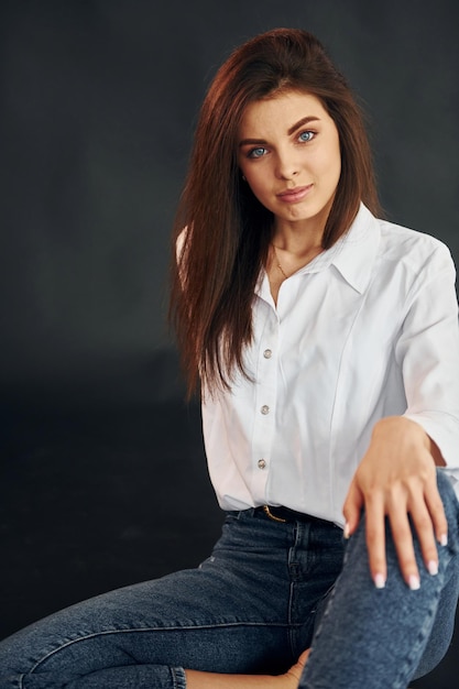 De camisa branca e jeans azul Jovem linda está posando para a câmera no estúdio