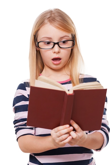 De jeito nenhum! menina surpresa lendo livro e mantendo a boca aberta enquanto fica em pé, isolado no branco