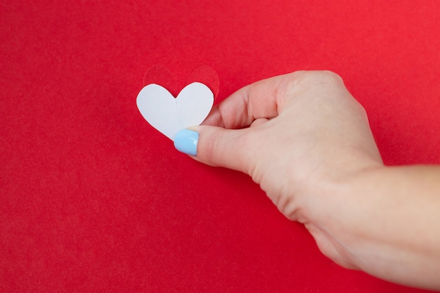 Dé llevar a cabo un corazón blanco en un fondo rojo. Fondo para el día de san valentín.