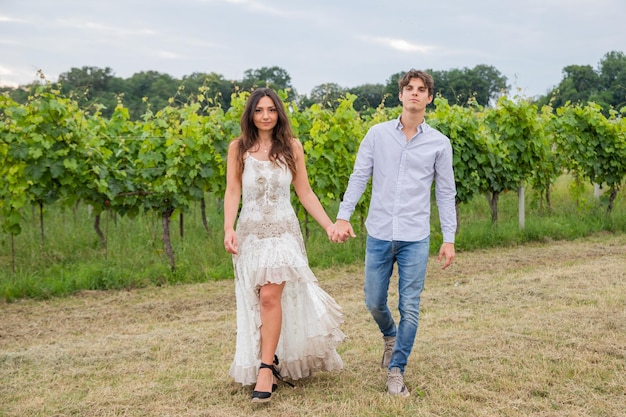 De mãos dadas o casal modelo ginga pelos vinhedos do campo